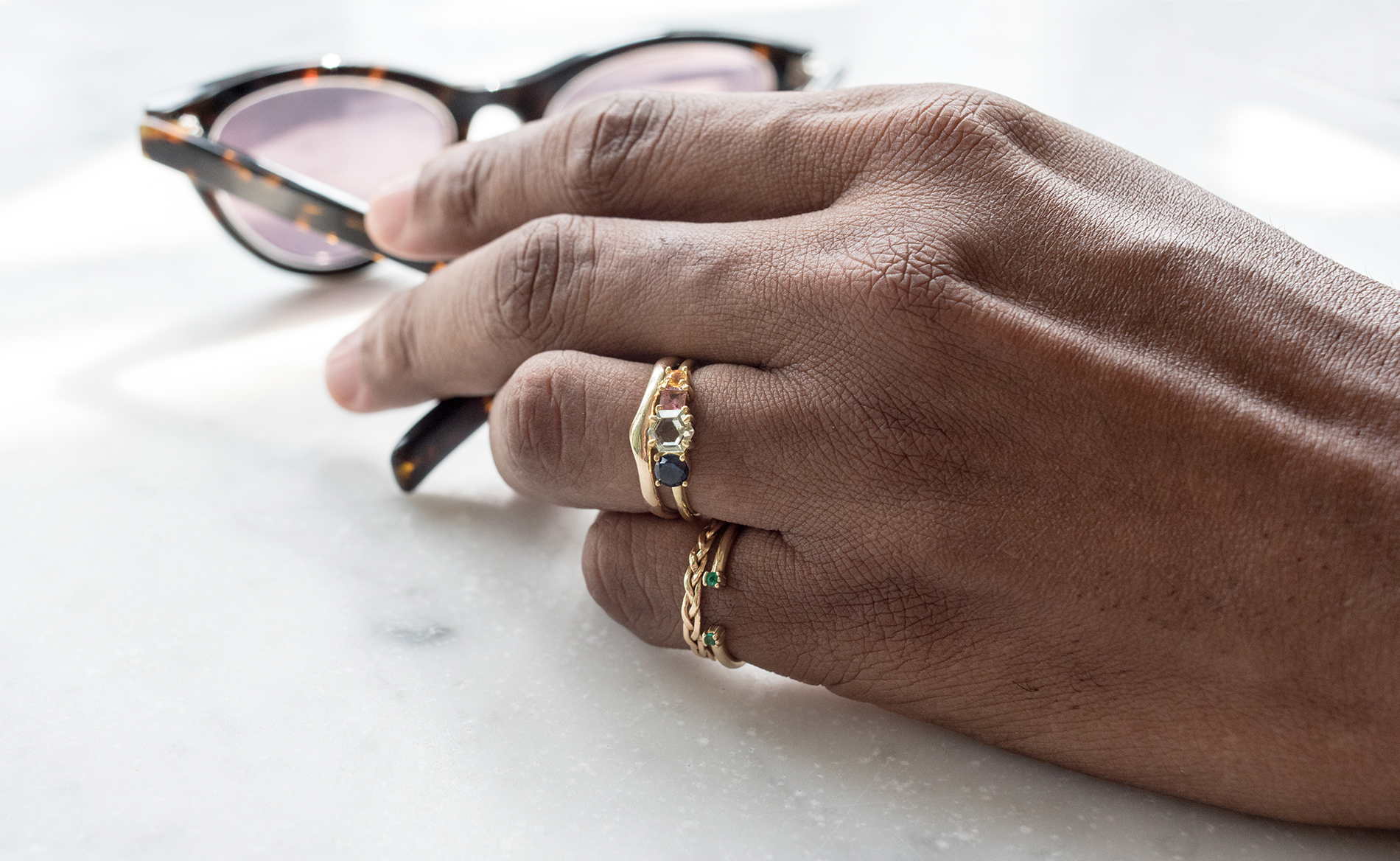 Masculine hand wearing Linear Hex Sapphire Ring, Reticulated Two Band, Open Lash Ring, and Aldine Thin Band