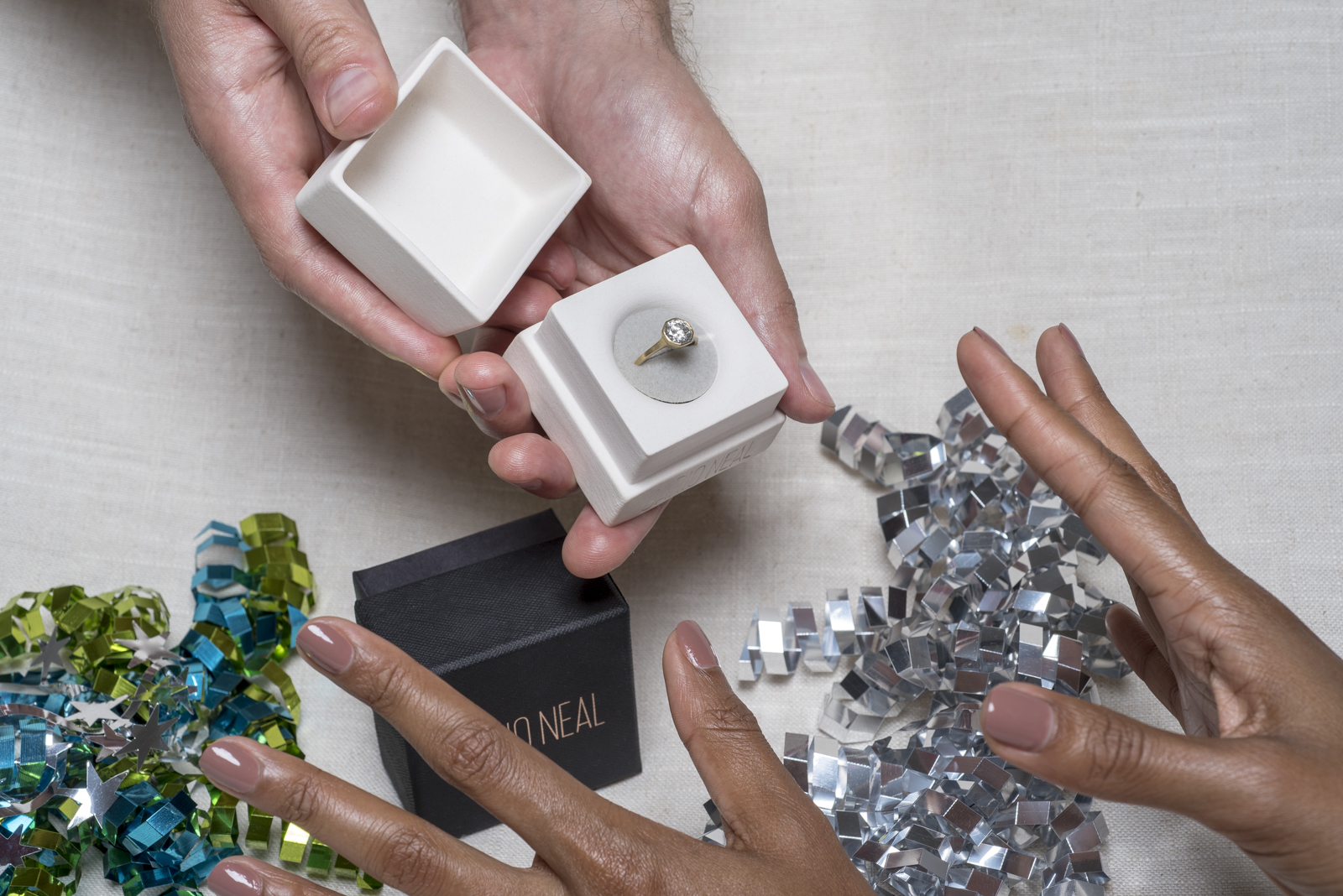 Photograph of a man holding a jewelry box with an engagement ring inside 