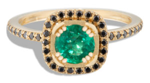 A modern interpretation of a halo ring showcasing an emerald center stone complemented by a surrounding black diamond halo.