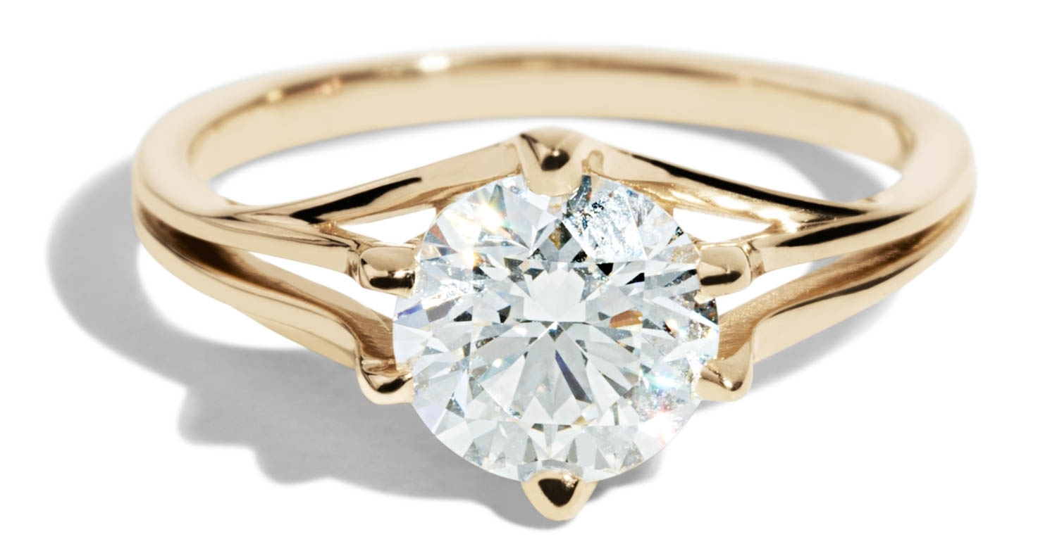 Close up of a solitaire yellow-gold ring featuring a single diamond center stone