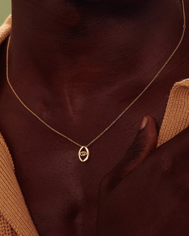 Person wearing yellow-gold necklace pendant with a morganite center stone
