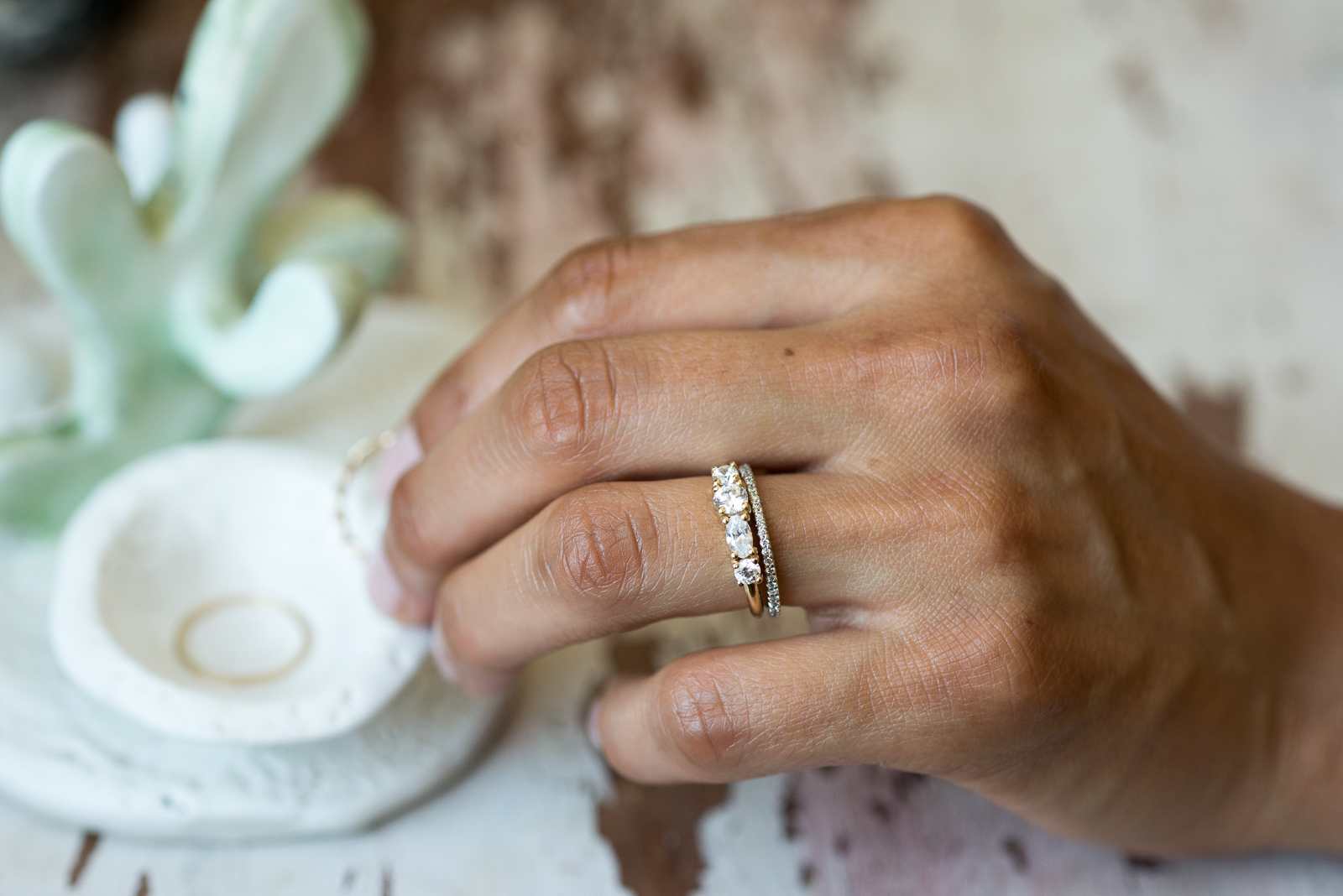A beautiful ring delicately held by a woman's hand on a table.