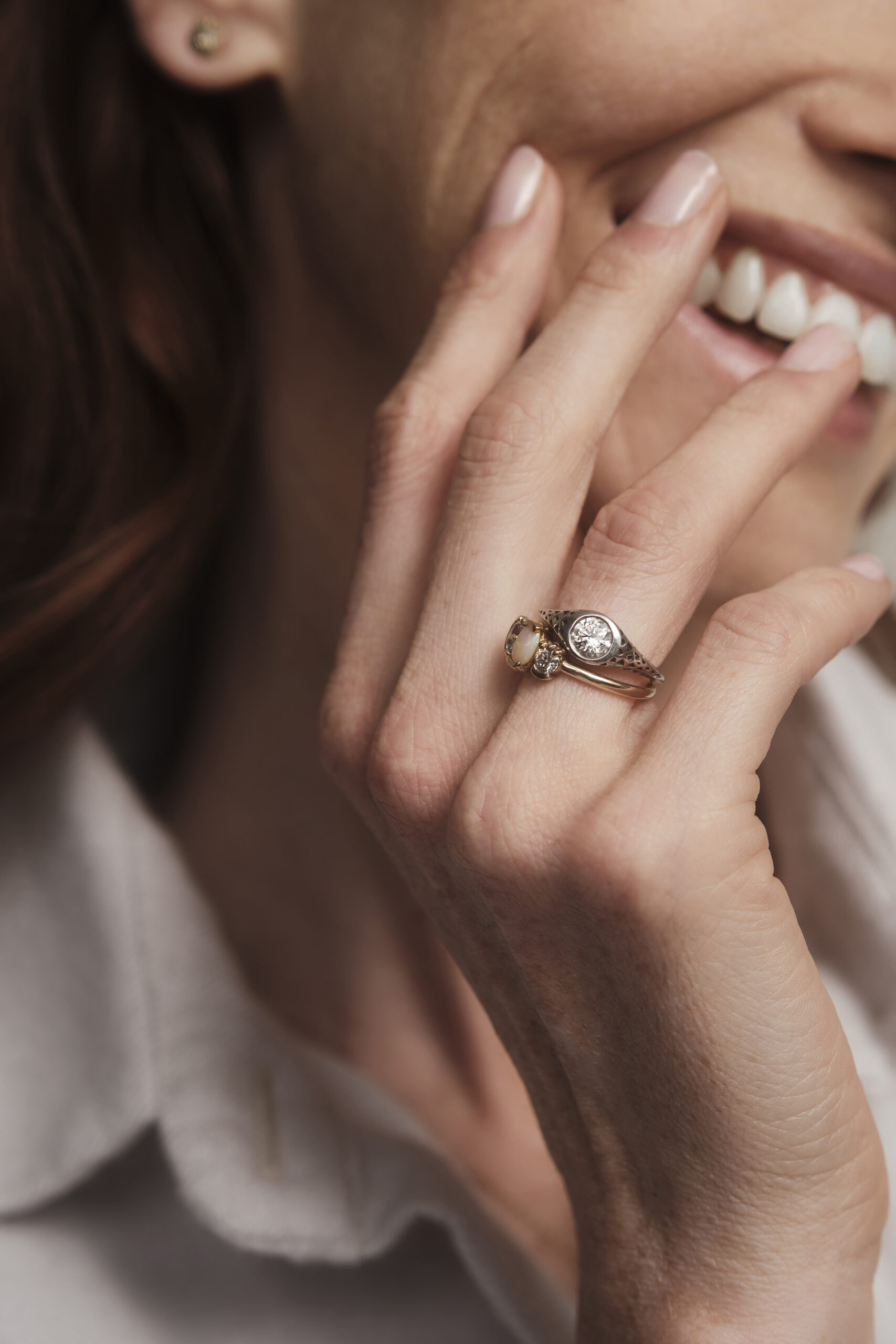 woman with hand gracefully placed on cheek, showcasing a stack of rings on her ring finger. 