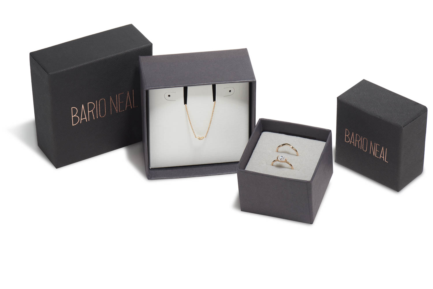 Two jewelry boxes placed aesthetically. One holds a diamond necklace; the other holds two rings. sustainable packaging